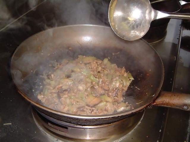 Food Chinese meal of squid being stir fried in a wok with gree peppers  onions and black bean sauce