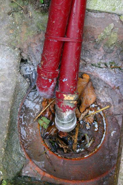 Two Drain Pipes Running into an Old Grid